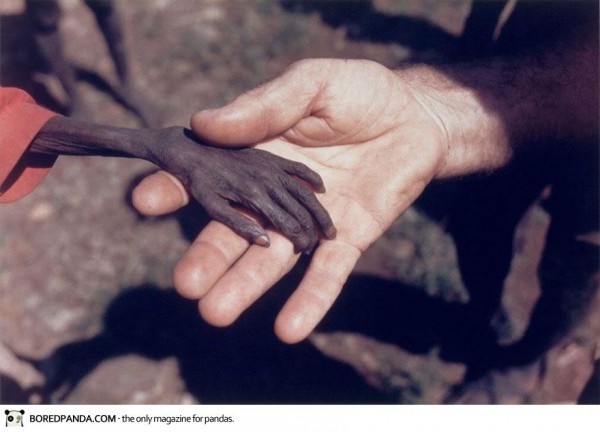 Avril 1980, Karamoj, Ouganda, Un missionnaire prend la main d'un enfant mourant de famine